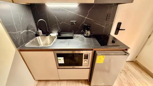 a small kitchen with a sink and a microwave at Lujosas suites XOE in Quito