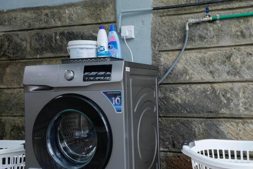 a washing machine sitting next to a brick wall at Modern Guest House 2BR in Nakuru