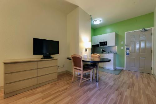 a room with a table and a tv and a kitchen at Studio 6 Toronto - Mississauga with Kitchenettes in Mississauga