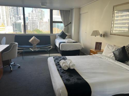 a hotel room with two beds and a desk at Paxsafe Sydney Hyde Park Private Apartments in Sydney