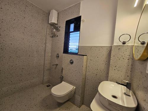 a bathroom with a toilet and a sink and a window at Rustic 1BHK Apartment, Gym, Pool, Amenities - Near Candolim Beach in Candolim