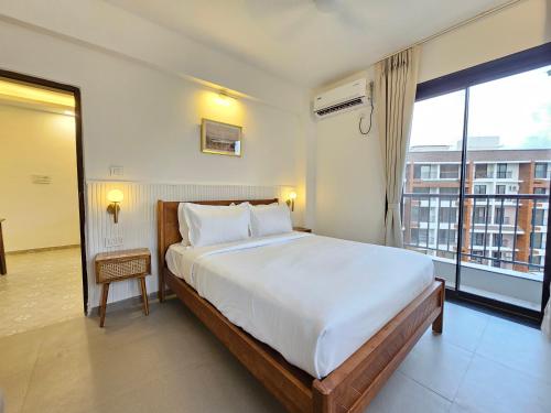 a bedroom with a large bed and a large window at Rustic 1BHK Apartment, Gym, Pool, Amenities - Near Candolim Beach in Candolim