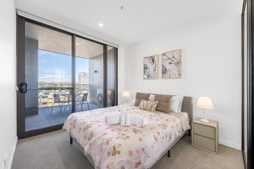 a bedroom with a large bed and a balcony at Cozy Woden Stay, Hospital, Mall, Pool, Parking in Phillip