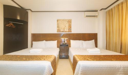 马尼拉The Shilla Philia Hotel by RedDoorz的酒店房间有两张床，床单是白色的