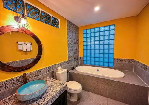 a bathroom with a tub and a toilet and a sink at Hometown Signature Retreat Villa Hoi An in An Bang