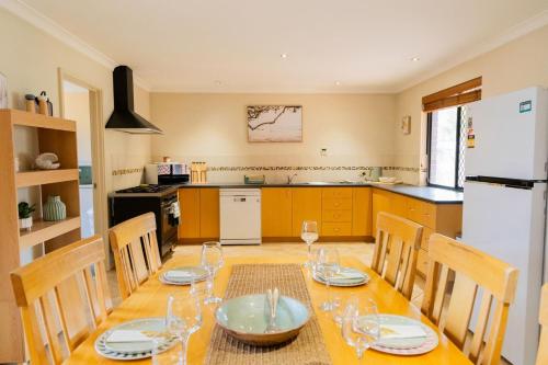 a kitchen with a wooden table with chairs and a white refrigerator at Busselton Breeze in Busselton