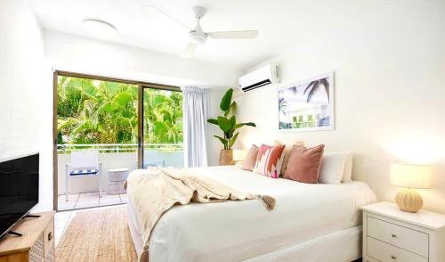 Un dormitorio blanco con una cama grande y un televisor. en Sunny Private Oasis Stroll to Noosa Main Beach, en Noosa Heads