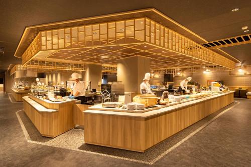 a group of chefs preparing food in a kitchen at Ooedo Onsen Monogatari Premium Saiki Bekkan in Misasa