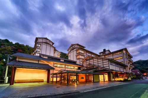 a large building on a street with a cloudy sky at Ooedo Onsen Monogatari Premium Saiki Bekkan in Misasa