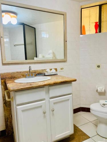 a bathroom with a sink and a mirror and a toilet at Marina Cabo Plaza "Casa Pura Vida" 108A in Cabo San Lucas