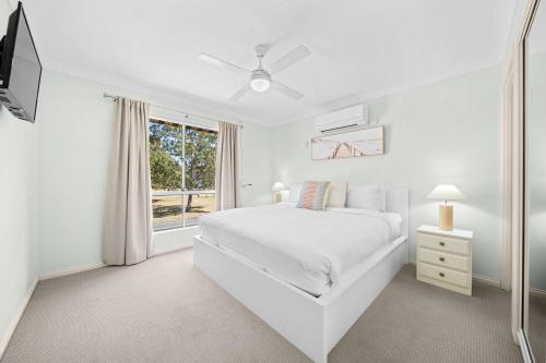 a white bedroom with a white bed and a window at 2BRM Self Contained Apt - Pumicestone Passage View in Bellara