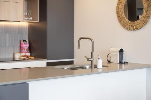 a kitchen counter with a sink and a mirror at Cosy Woden Apt Near Canberra Hospital,Transport in Phillip