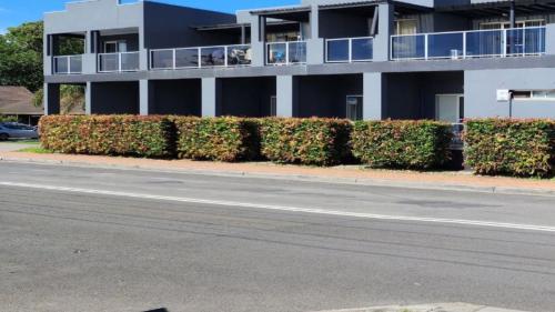 a building with a row of bushes in front of a street at Jopen Motel Unit 6 in Sussex inlet