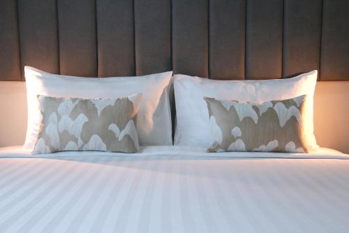 a bed with white sheets and pillows at Xen Pool Access in Chalong 
