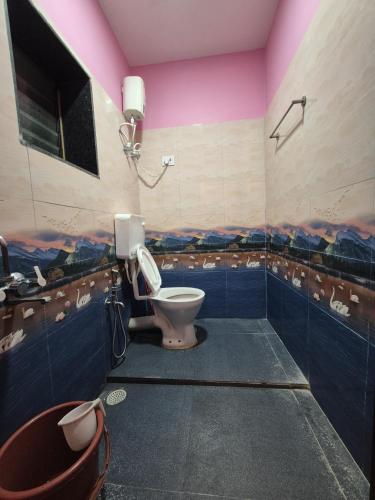 een badkamer met een toilet en een roze plafond bij Swayambhu Resort in Malvan