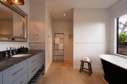 a bathroom with two sinks and a tub and a bathtubermott at The Brooklet in Byron Bay