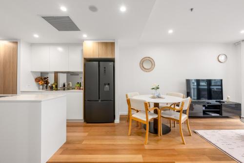 a kitchen with a table and a black refrigerator at Canberra Central,Modern 2BR Getaway, Parking,ANU in Braddon