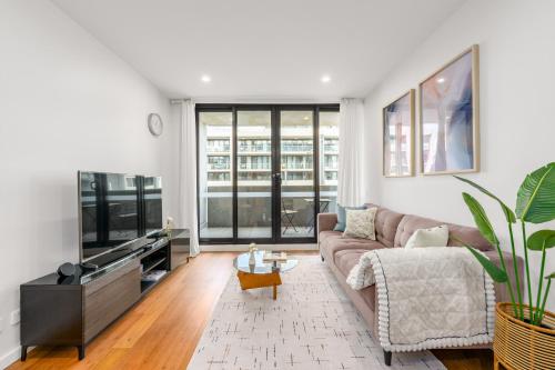 a living room with a couch and a flat screen tv at Canberra Central,Modern 2BR Getaway, Parking,ANU in Braddon