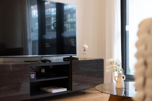 a living room with a flat screen tv on a entertainment center at Canberra Central,Modern 2BR Getaway, Parking,ANU in Braddon