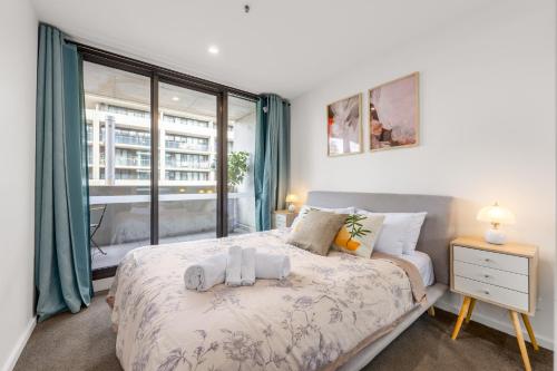a bedroom with a bed and a large window at Canberra Central,Modern 2BR Getaway, Parking,ANU in Braddon