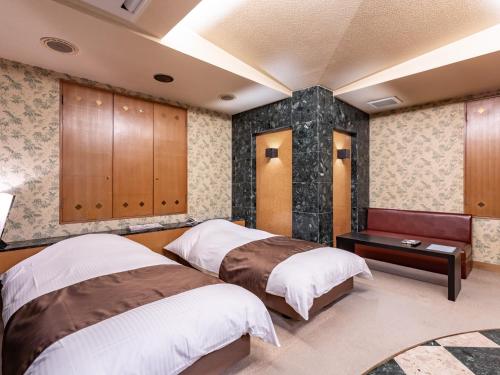 a bedroom with two beds and a table at Tabist HOTEL SWEETWATER in Takamatsu