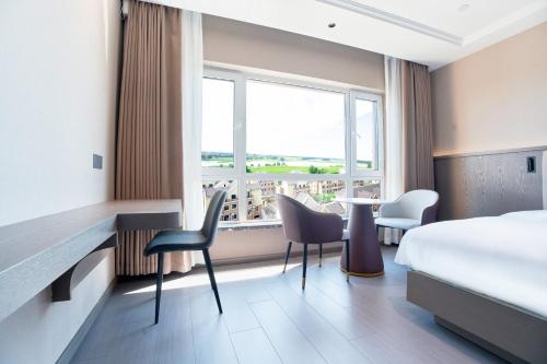um quarto de hotel com uma cama, uma mesa e cadeiras em Harbin Airport Lake View Hotel em Harbin