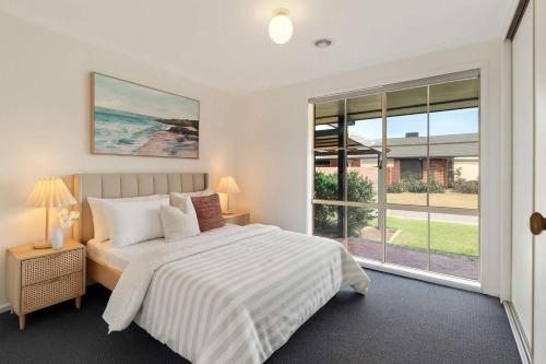a white bedroom with a bed and a large window at Family Oasis near Watergardens Parking in Sydenham