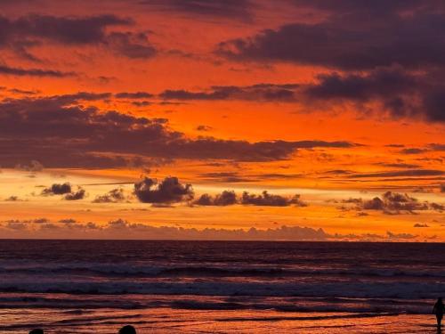 a sunset over the ocean with people walking on the beach at Casa Vacacional Valles de Olon in Santa Elena