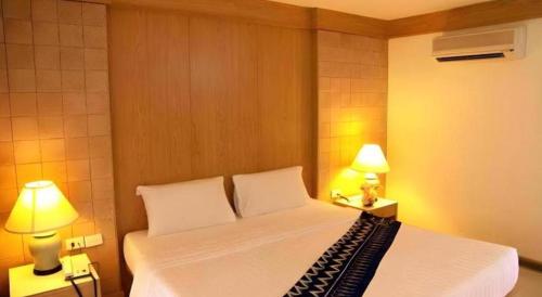 a bedroom with a white bed with two lamps at Phi Phi Banyan Villa in Phi Phi Don