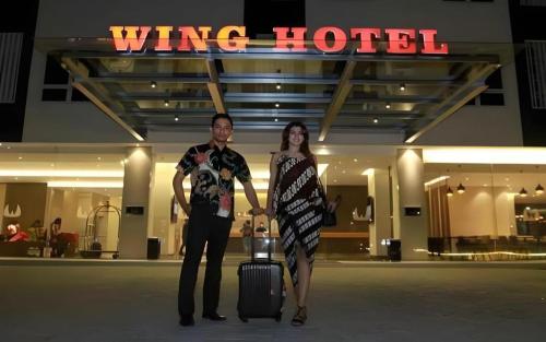 a man and woman standing in an airport with a suitcase at Wing Hotel Kualanamu Airport in Medan
