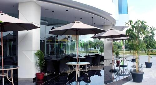 a patio with tables and umbrellas in a building at Wing Hotel Kualanamu Airport in Medan