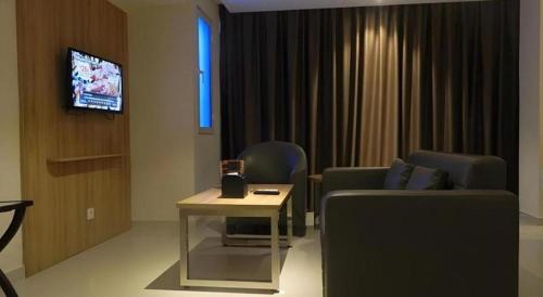 a living room with a couch and a tv at Wing Hotel Kualanamu Airport in Medan