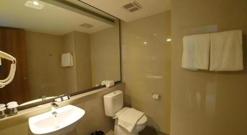 a bathroom with a sink and a toilet and a mirror at Wing Hotel Kualanamu Airport in Medan