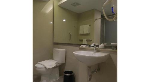 a bathroom with a sink and a toilet and a mirror at Wing Hotel Kualanamu Airport in Medan