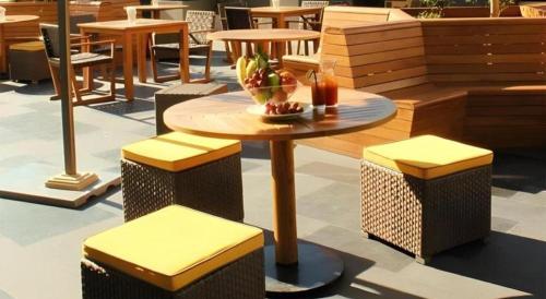 a table and stools with a bowl of fruit on it at F1 Hotel Manila in Manila