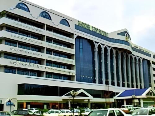 a large building with cars parked in a parking lot at The CentrePoint Hotel in Bandar Seri Begawan