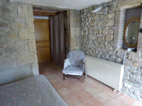a room with a chair and a stone wall at Domaine Chanoine Rambert in Saint-André-dʼOlérargues