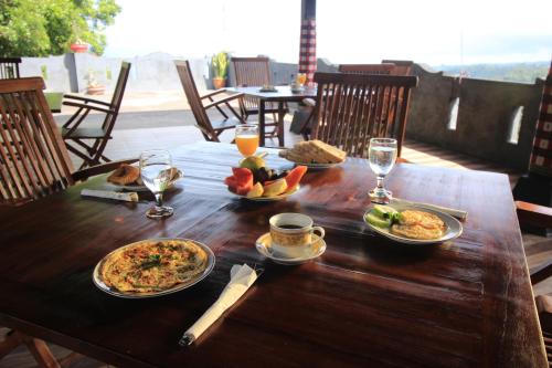 a wooden table with food and glasses of wine at Adila Warung and Homestay in Munduk