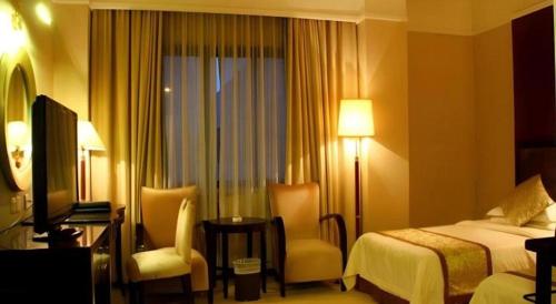 a hotel room with a bed and chairs and a television at Quanzhou Royal Prince Hotel in Quanzhou