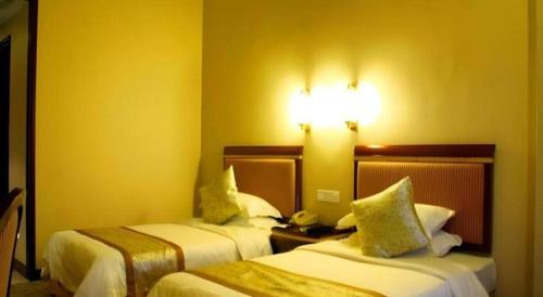a hotel room with two beds and a light on the wall at Quanzhou Royal Prince Hotel in Quanzhou