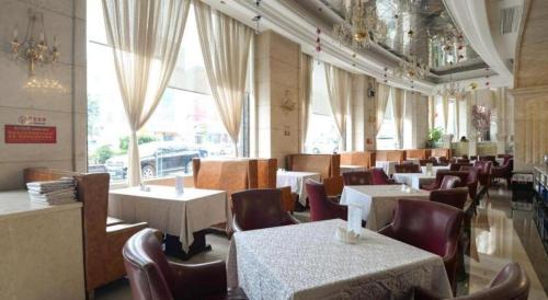 a dining room with tables and chairs and windows at Regency Hotel in Dongguan
