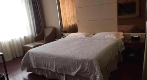 a bedroom with a large bed and a chair at Regency Hotel in Dongguan