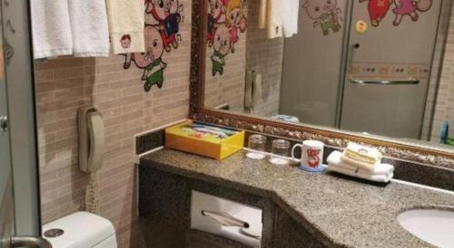 a bathroom with a sink and a mirror and a toilet at Dengfeng Chanwu Hotel in zhengzhou