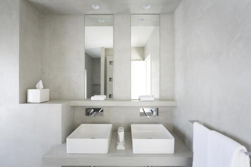 a white bathroom with two sinks and a mirror at Château Autignac in Autignac