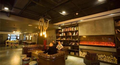 two people sitting in a room with a fireplace at James Joyce Coffetel Chengdu Jianshe Road Dongjiao Jiyi Square in Chengdu