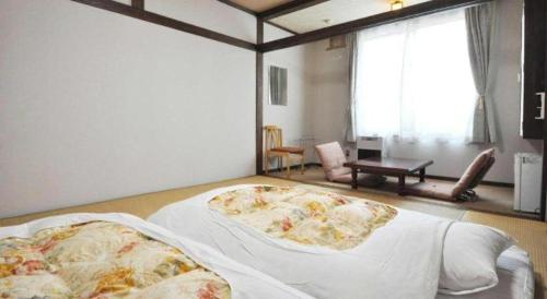 a bedroom with two beds and a large window at Yunosawa Onsen Mori no Shiki in Shimukappu