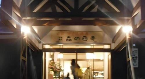 a woman is walking into a restaurant at night at Yunosawa Onsen Mori no Shiki in Shimukappu