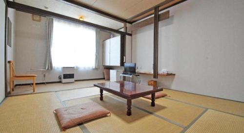 a living room with a coffee table and a large window at Yunosawa Onsen Mori no Shiki in Shimukappu