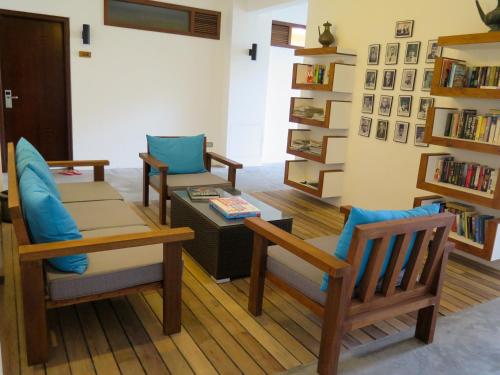 a living room with two chairs and a table and bookshelves at Aveyla Manta Village in Dharavandhoo