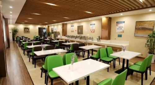 a restaurant with green chairs and tables in a room at GreenTree Inn Xuancheng Jingxian Wannan First Street Express Hotel in Xuanzhou